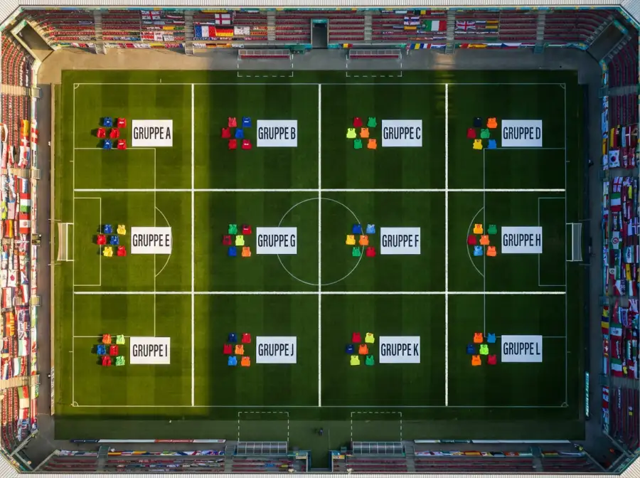 Übersicht der 12 WM-Gruppen 2026 mit Nationalflaggen auf einem Fussballrasen